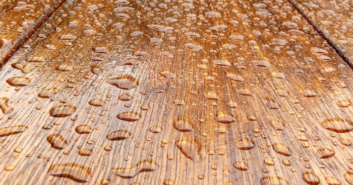 Water beading and running off a timber surface treated with a water-repellent wood coating.