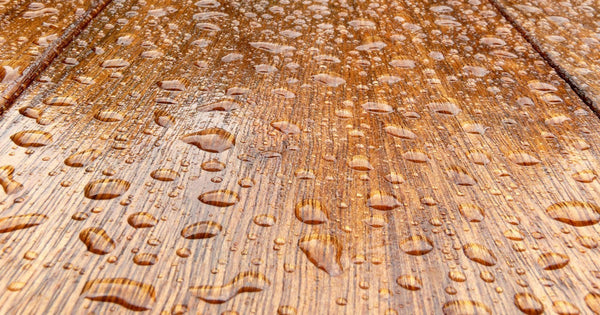 Water beading and running off a timber surface treated with a water-repellent wood coating.